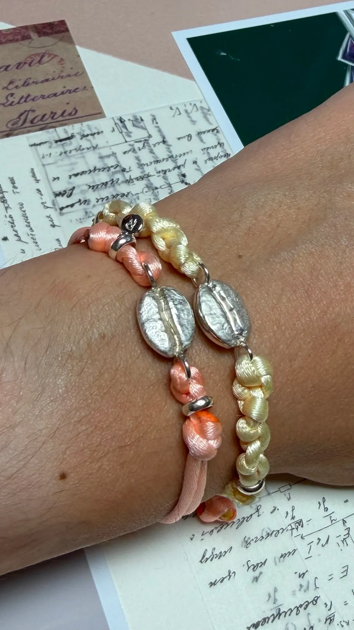 Deux bracelets « Le grain » portés au poignet, cordons teints à la main, grains d'argent.